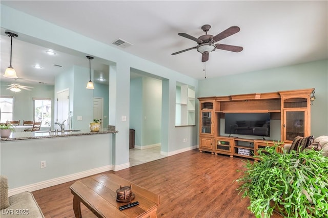 living room featuring hardwood / wood-style flooring, built in features, and ceiling fan