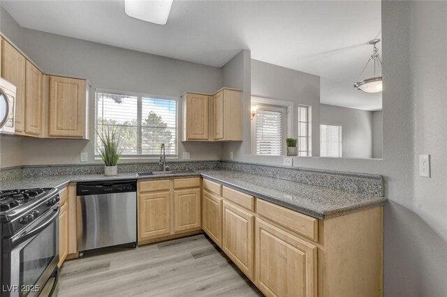 5250 S Rainbow Blvd Unit 2165, Las Vegas, NV 89118 - kitchen featuring appliances with stainless steel finishes, light brown cabinetry, light wood-style flooring, a peninsula, and decorative light fixtures