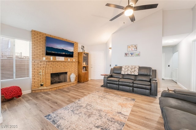 living room featuring a brick fireplace, hardwood / wood-style floors, high vaulted ceiling, and ceiling fan