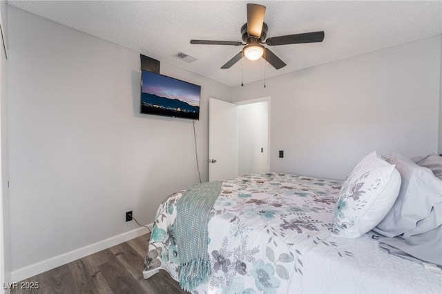 bedroom with ceiling fan, dark hardwood / wood-style floors, and a textured ceiling