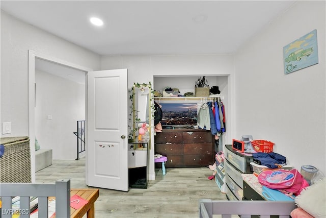 bedroom with light hardwood / wood-style floors and a closet