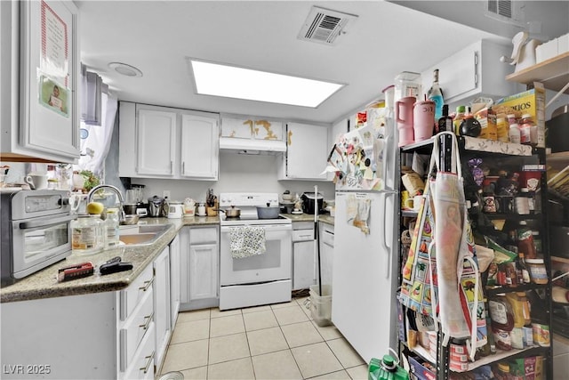 kitchen featuring sink, white appliances, light tile patterned floors, and white cabinets