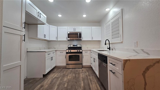 kitchen with appliances with stainless steel finishes, a sink, and white cabinetry