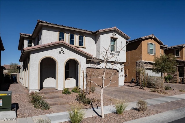 mediterranean / spanish-style home featuring a garage, driveway, a tiled roof, and stucco siding