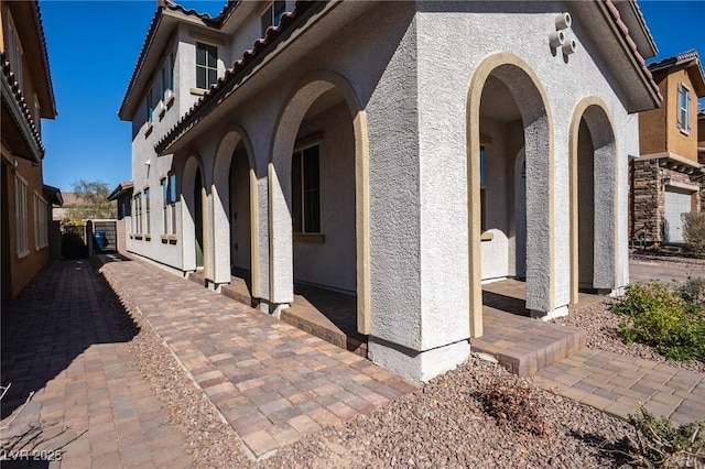 view of property exterior featuring a tiled roof, a patio area, and stucco siding