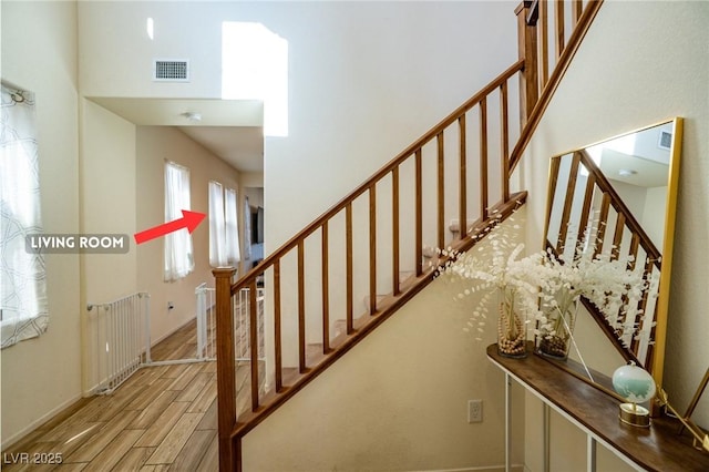 stairs with a towering ceiling, wood tiled floor, and visible vents