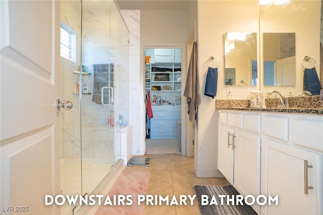 full bath featuring a spacious closet, a stall shower, tile patterned flooring, and vanity