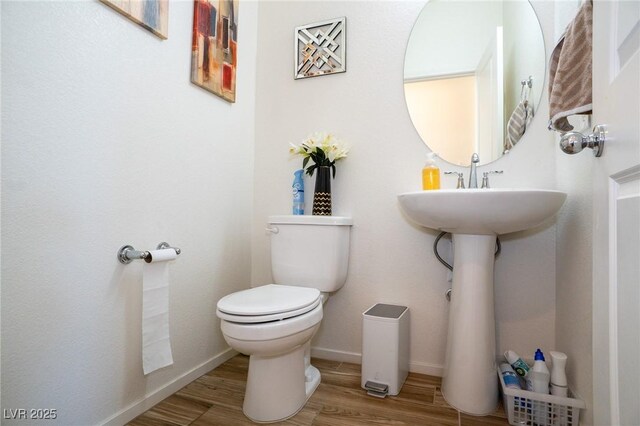 bathroom with baseboards, toilet, and wood finished floors