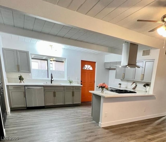 kitchen featuring a peninsula, island exhaust hood, light countertops, stainless steel dishwasher, and a sink