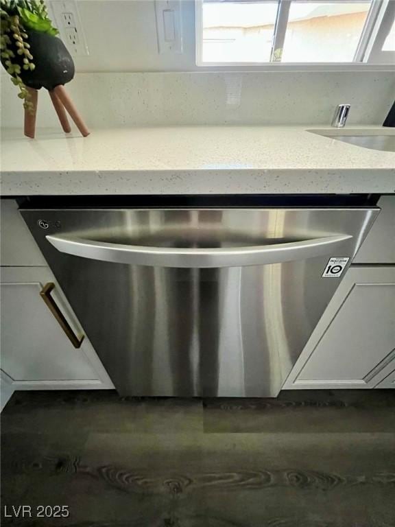 room details with white cabinets, stainless steel dishwasher, and light stone countertops