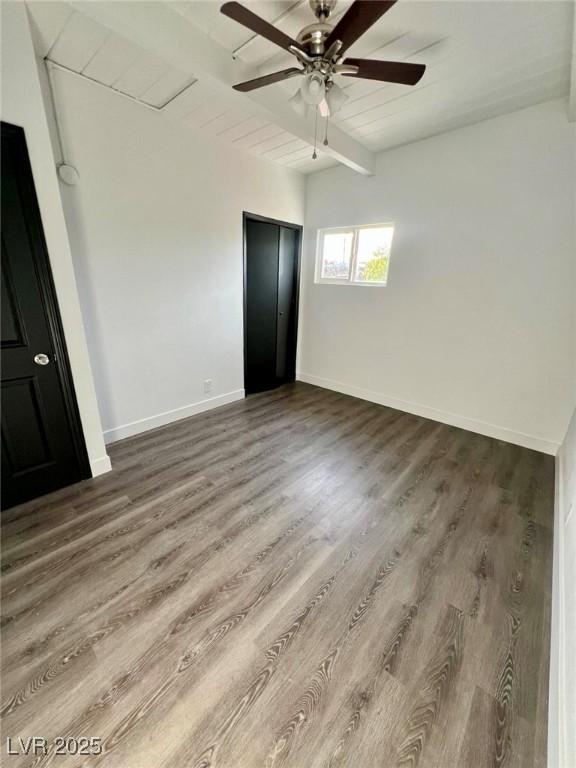 unfurnished bedroom with baseboards, wooden ceiling, ceiling fan, beamed ceiling, and wood finished floors