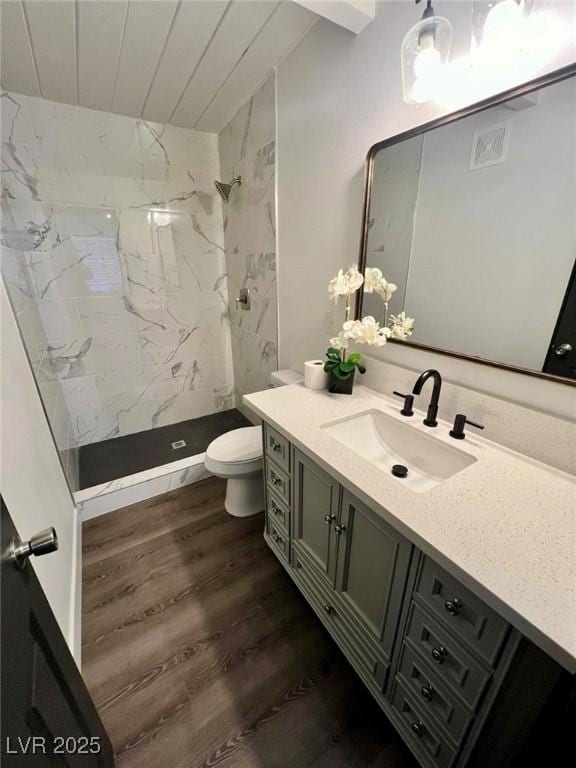 bathroom featuring toilet, wood finished floors, visible vents, vanity, and a stall shower