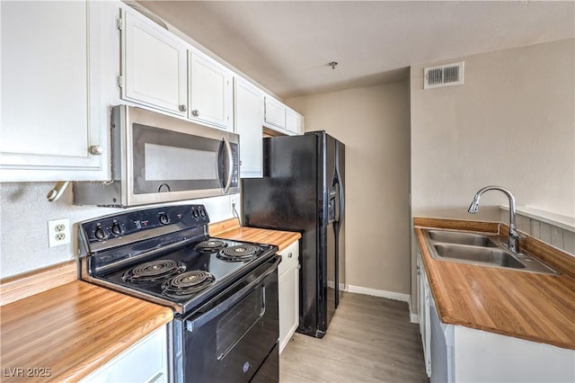 kitchen featuring sink, white cabinetry, butcher block counters, black appliances, and light hardwood / wood-style floors