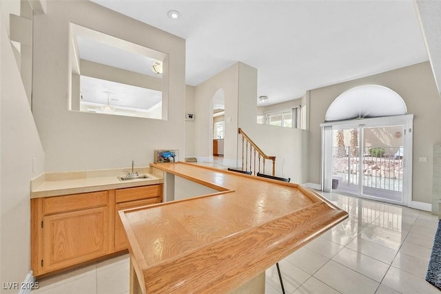 kitchen with light brown cabinetry, sink, and light tile patterned flooring