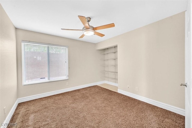 carpeted empty room featuring ceiling fan and built in shelves
