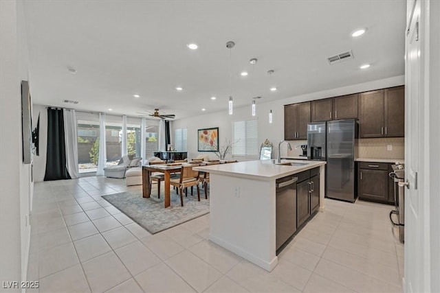 kitchen with dark brown cabinetry, sink, a center island with sink, light tile patterned floors, and stainless steel appliances