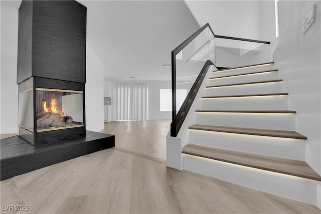 staircase featuring hardwood / wood-style flooring and a multi sided fireplace