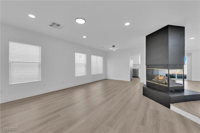 living room featuring a multi sided fireplace and light hardwood / wood-style flooring