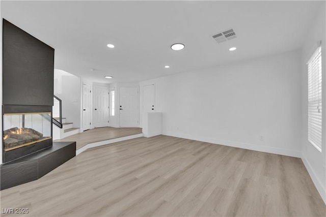 unfurnished living room featuring a tiled fireplace and light wood-type flooring