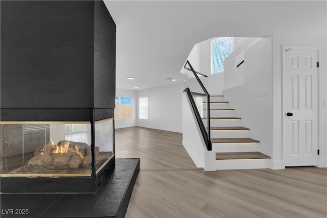 staircase featuring a multi sided fireplace and wood-type flooring