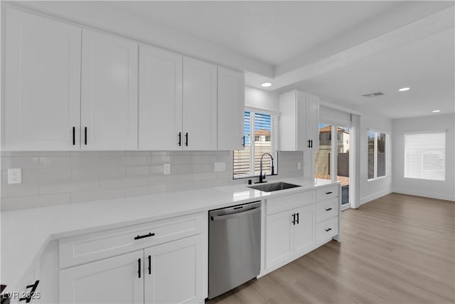 kitchen with white cabinetry, sink, stainless steel dishwasher, and light hardwood / wood-style floors