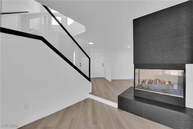 staircase featuring hardwood / wood-style floors and a multi sided fireplace