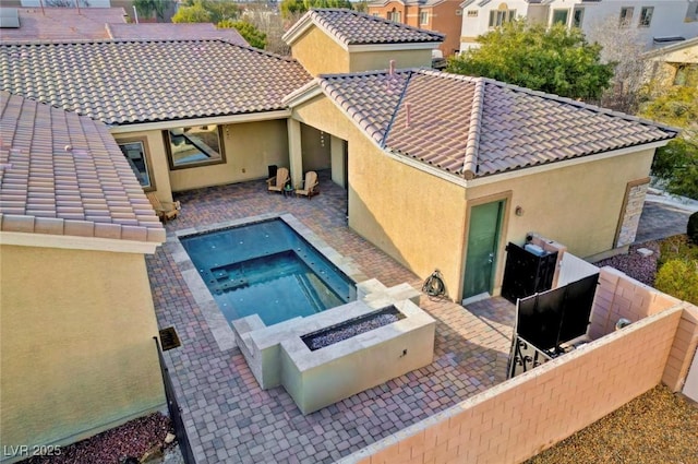 exterior space featuring a jacuzzi, a patio area, and an outdoor fire pit