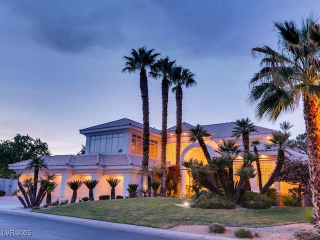 mediterranean / spanish-style house featuring a lawn, concrete driveway, and a tile roof