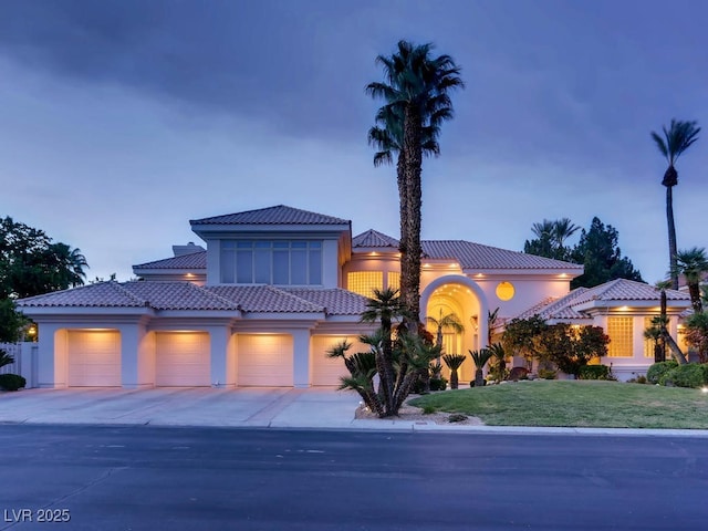 view of front of property featuring stucco siding, driveway, a yard, a garage, and a tiled roof