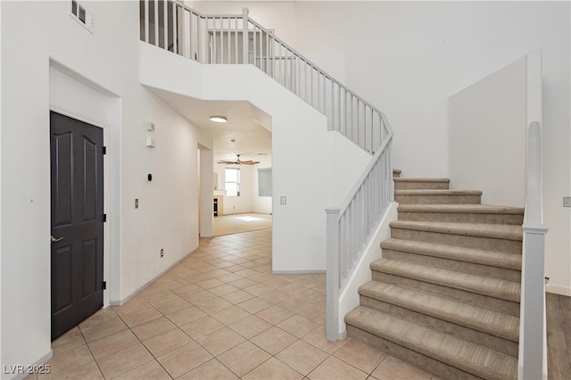 tiled entrance foyer with ceiling fan and a high ceiling