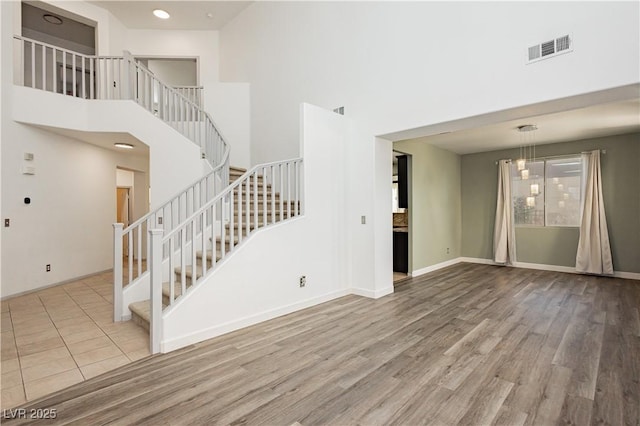 unfurnished living room with a towering ceiling and light hardwood / wood-style flooring