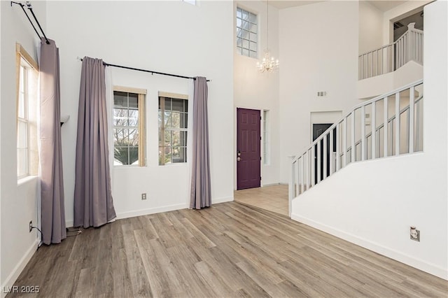 foyer entrance featuring light hardwood / wood-style floors, a chandelier, and a high ceiling