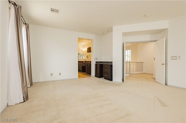 interior space featuring connected bathroom and light colored carpet