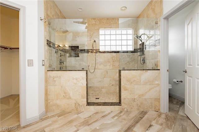 bathroom with a tile shower and toilet