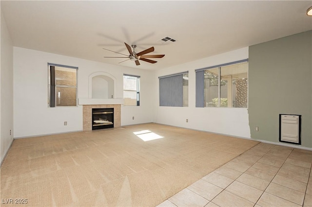 unfurnished living room with a tile fireplace, light carpet, and ceiling fan