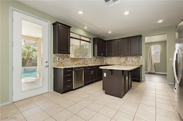 kitchen with tasteful backsplash, stainless steel dishwasher, a center island, and dark brown cabinets