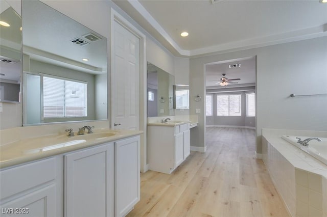 bathroom with vanity, hardwood / wood-style floors, tiled bath, and ceiling fan