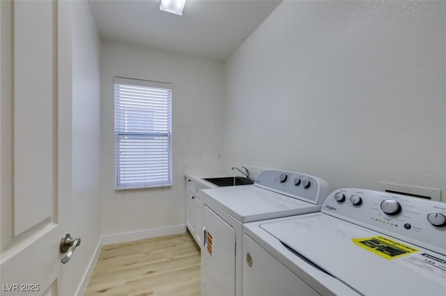 laundry area featuring light hardwood / wood-style floors, cabinets, separate washer and dryer, and sink