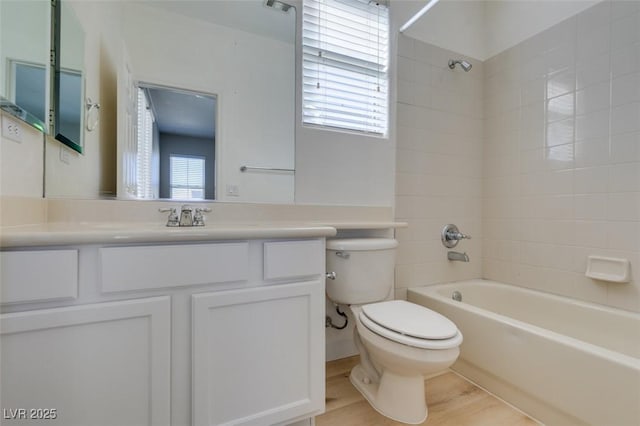 full bathroom with tiled shower / bath, vanity, toilet, and hardwood / wood-style floors