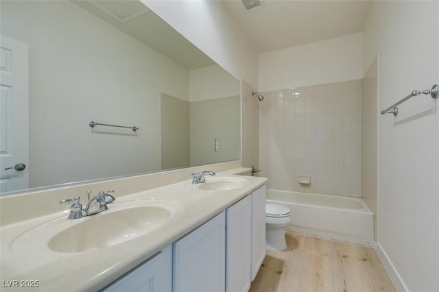 full bathroom featuring tiled shower / bath, vanity, toilet, and hardwood / wood-style floors