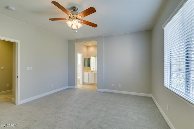 unfurnished bedroom featuring connected bathroom, light colored carpet, and ceiling fan