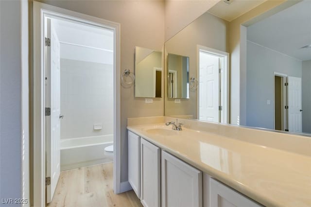 full bathroom with hardwood / wood-style flooring, shower / tub combination, vanity, and toilet