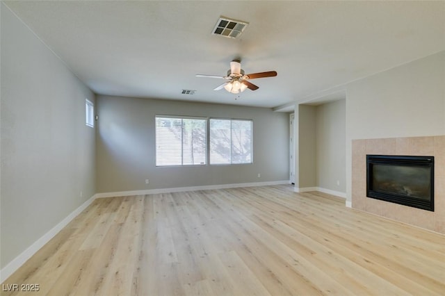 unfurnished living room with ceiling fan, a fireplace, and light wood-type flooring