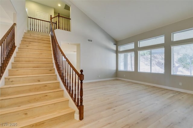 stairs featuring hardwood / wood-style floors, plenty of natural light, and high vaulted ceiling