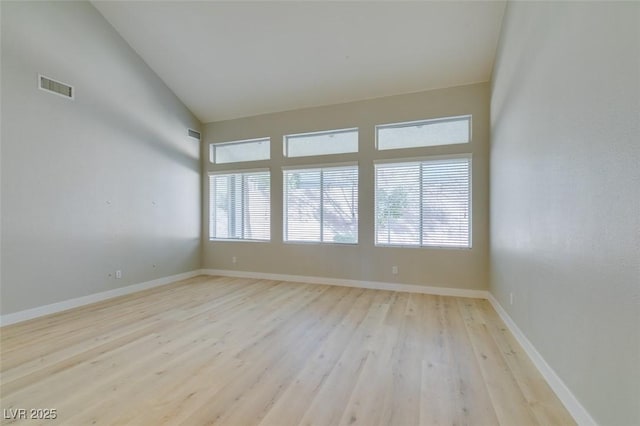 spare room with high vaulted ceiling and light hardwood / wood-style flooring