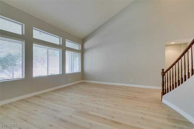 spare room with light hardwood / wood-style flooring and high vaulted ceiling