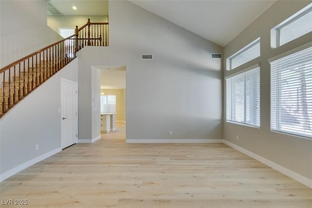 unfurnished room featuring high vaulted ceiling and light wood-type flooring