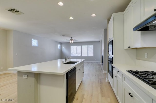 kitchen with sink, black appliances, white cabinets, and a center island with sink