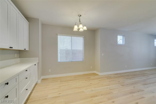 unfurnished dining area with a notable chandelier and light hardwood / wood-style flooring