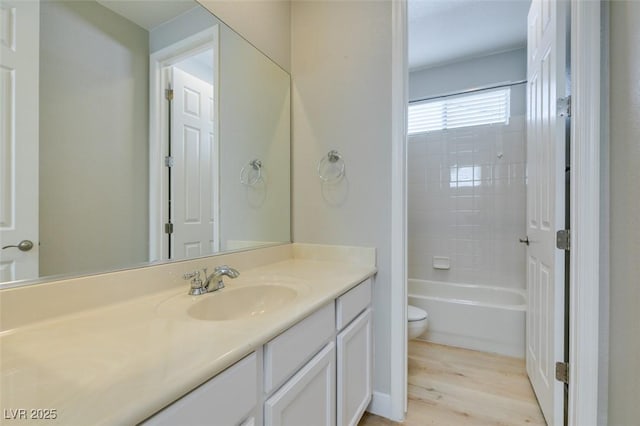 full bathroom featuring tiled shower / bath, vanity, toilet, and hardwood / wood-style floors